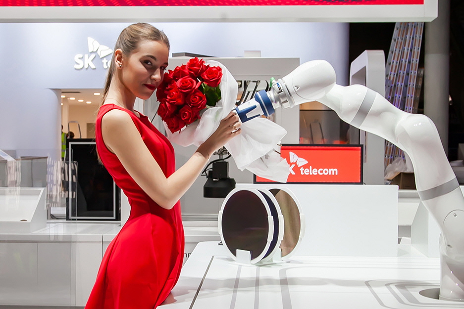SK텔레콤 모델이 전시관 내 '5G 커넥티드 팩토리' 솔루션의 로봇이 전해주는 꽃다발을 건네받고 있다.(사진:SKT)