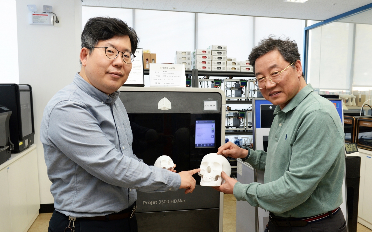 ETRI 연구진이 3D 프린터를 이용해 의료 시뮬레이션을 위한 머리뼈 모형을 들고 기술을 설명하는 모습으로 왼쪽부터 이병남 박사, 전종흥 박사(사진:ETRI)