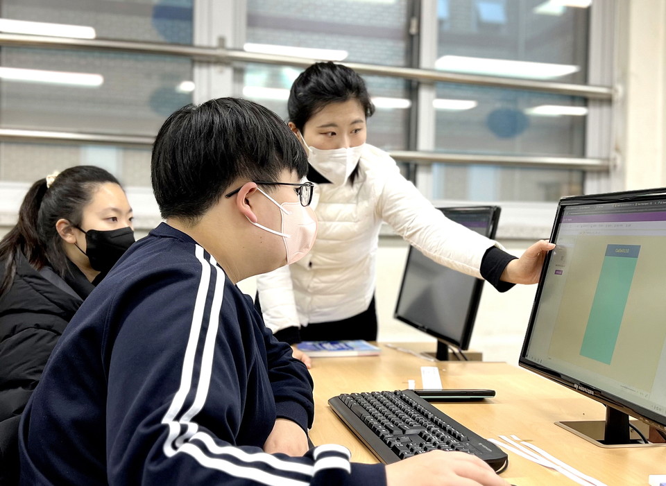 운암중학교 인공지능 캠프에서 주도적인 역할을 한 김소연 선생님(오른쪽)이 프로젝트에서 학생에게 도움을 주고 있는 모습.