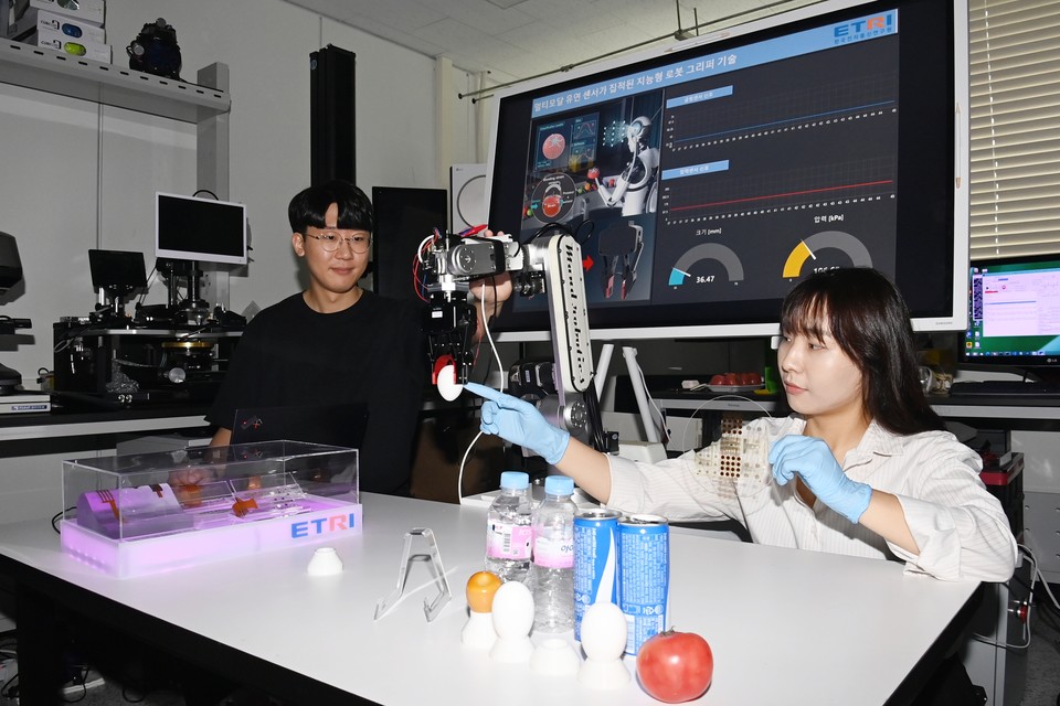 지능형부품센서연구실 주훈표 연구원(왼쪽)과 민유림 학생연구원이 멀티 모달 유연 센서가 집적된 지능형 로봇 그리퍼 기술로 달걀 잡는 실험하는 모습