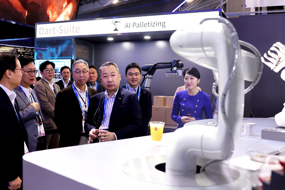 박정원 두산그룹 회장(가운데)과 박지원 그룹부회장(왼쪽)이 CES 2024 두산 부스에서 AI칵테일 로봇을 살펴보고 있다. (사진:두산그룹)